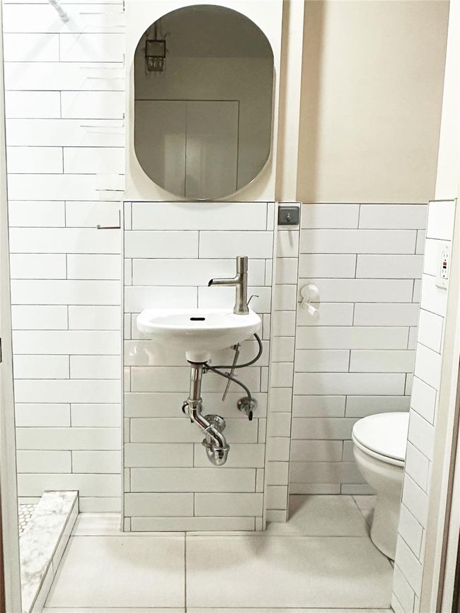Bathroom with tile walls, tile patterned flooring, a shower, and wainscoting | Image 21