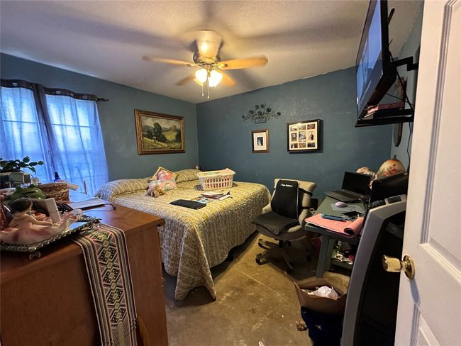 Bedroom with unfinished concrete floors and ceiling fan | Image 11