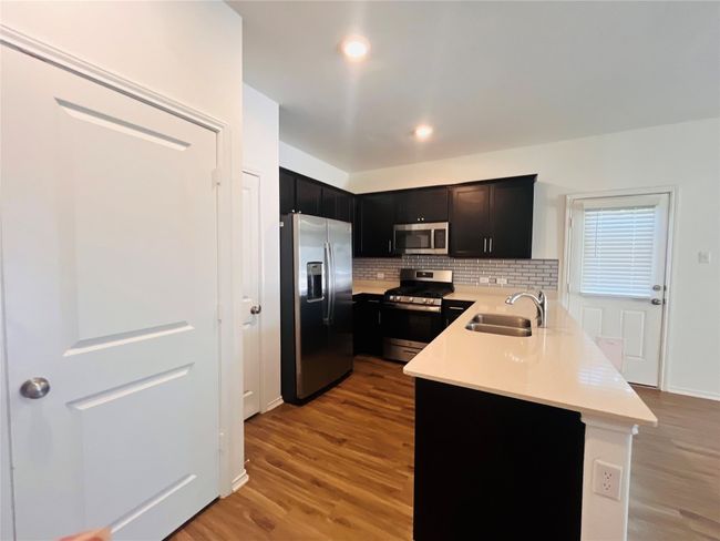 Kitchen with appliances with stainless steel finishes, light countertops, a peninsula, light wood-style flooring, and recessed lighting | Image 6