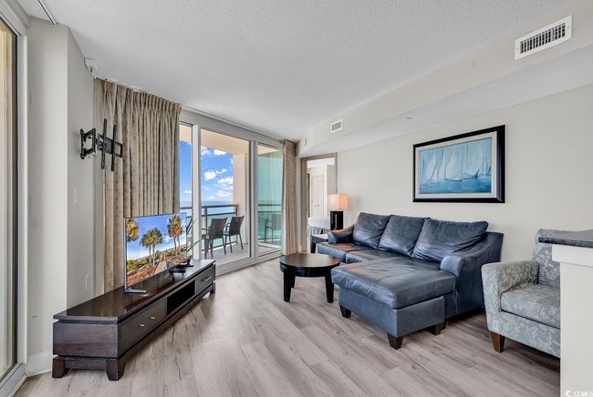 Living area featuring light wood-style floors, expansive windows, a textured ceiling, and visible vents | Image 14