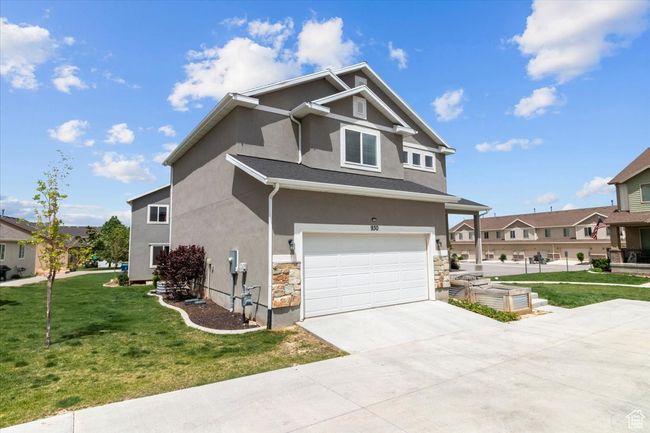 View of front of home with stucco siding, an attached garage, a front lawn, driveway, and stone siding | Image 5