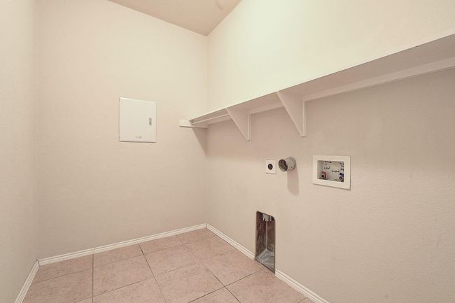 Laundry area featuring washer hookup, light tile patterned flooring, baseboards, and electric dryer hookup | Image 19