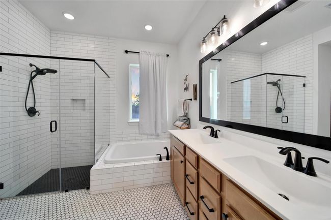 This modern bathroom features a spacious glass-enclosed shower, a luxurious soaking tub, and a double vanity with ample storage. The white subway tiles and hexagonal floor tiles add a sleek, contemporary touch. | Image 31