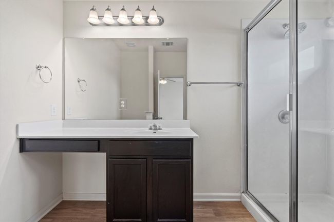A separate en-suite bath includes a step-in shower and single vanity. | Image 13