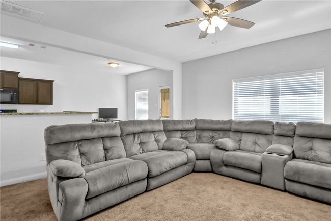 Living room with baseboards, carpet flooring, ceiling fan, and visible vents | Image 7