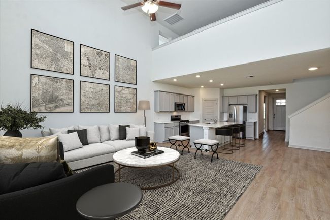 Living area with light wood finished floors, a ceiling fan, recessed lighting, and a towering ceiling | Image 5