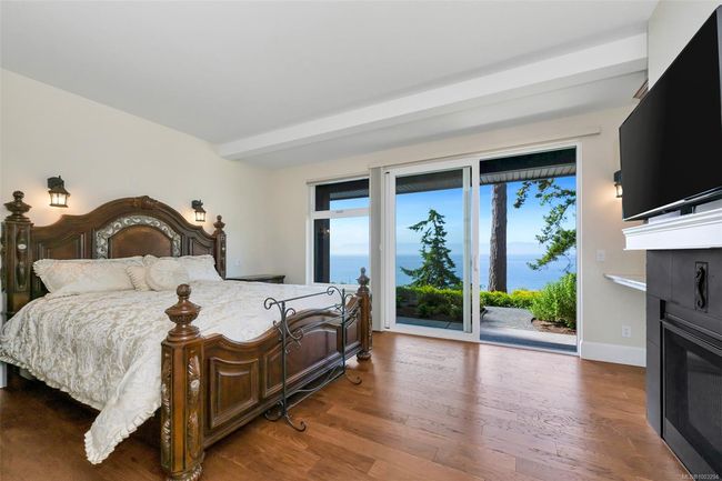 Bedroom with access to outside, a glass covered fireplace, and wood finished floors | Image 35