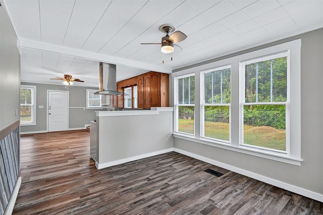 Kitchen featuring a ceiling fan, island range hood, dark wood-style flooring, and brown cabinetry | Image 6