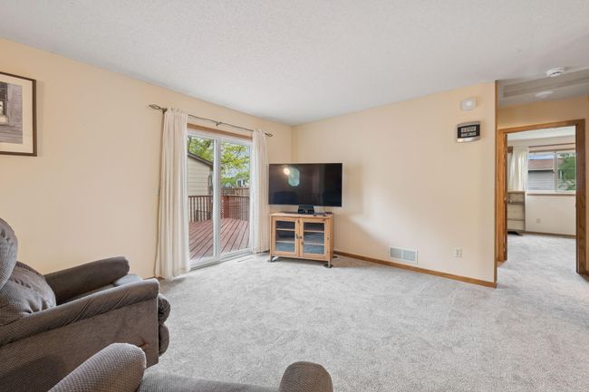 The living room features a patio door leading to a large deck. | Image 5