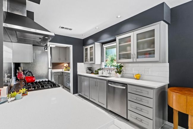 The neutral toned kitchen pleases any palette and invites joyful meal-making. Read-to -use with desirable modern finishes including SS appliances, Ceasarstone countertops, and more. | Image 5