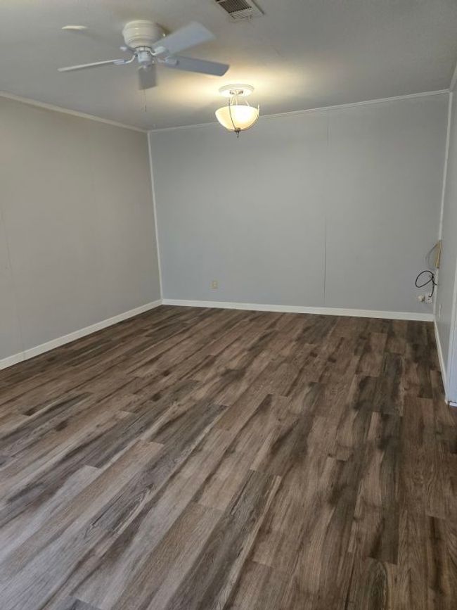 Spare room featuring ceiling fan, ornamental molding, and dark wood-type flooring | Image 27