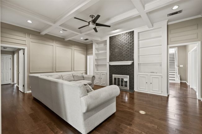 Living area with ceiling fan, beam ceiling, crown molding, coffered ceiling, and dark wood finished floors | Image 12