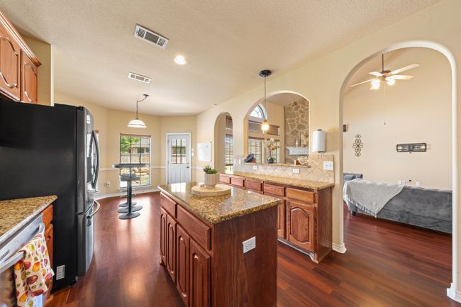 Kitchen featuring arched walkways, freestanding refrigerator, ceiling fan, and visible vents | Image 9