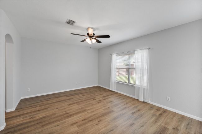 Empty room featuring ceiling fan, NEW laminate flooring, and arched walkways | Image 17