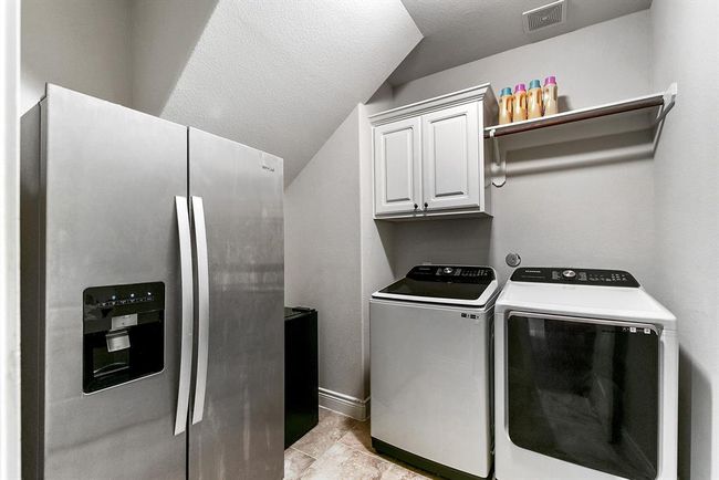 The oversized utility room features built-in cabinetry and shelving for added storage. You'll also notice the ample space, which easily accommodates an extra refrigerator, providing even more convenience and functionality. | Image 45