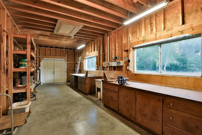 800 sq ft workshop is integral behind the garage with 2 separate workbenches each with purpose-designed cabinets and drawers, work sink, plenty of power points, lighting, and shelf storage. Large windows for natural light and also plenty of electric light. | Image 49