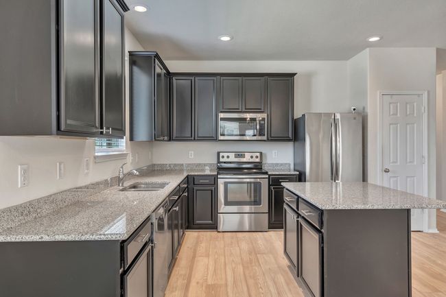 Kitchen with stainless steel appliances, light wood finished floors, light stone counters, and recessed lighting | Image 9