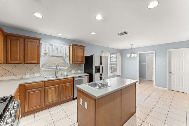Kitchen featuring a sink, backsplash, stainless steel appliances, and visible vents | Image 16