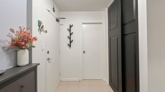 Doorway featuring light tile patterned flooring and a textured ceiling | Image 19