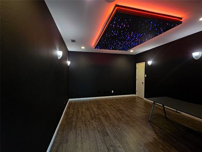 Cinema featuring a tray ceiling, wood finished floors, recessed lighting, and baseboards | Image 17