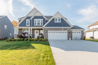 Craftsman-style home with a porch, a front lawn, and central AC unit | Image 1