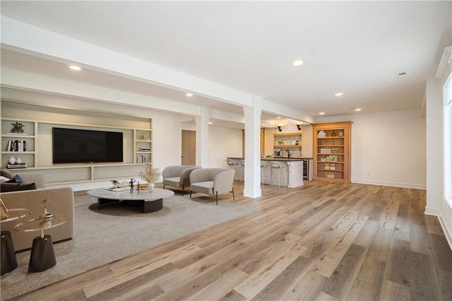 Living room with wood finished floors, recessed lighting, baseboards, and beverage cooler | Image 54