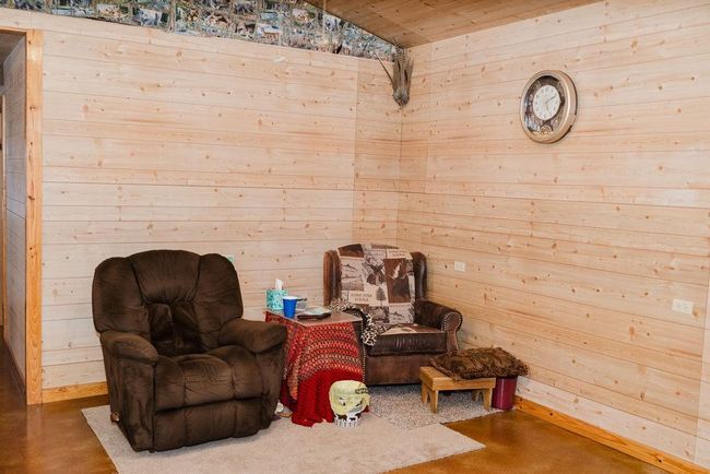 Living area featuring wood walls, finished concrete flooring, wooden ceiling, and lofted ceiling | Image 6