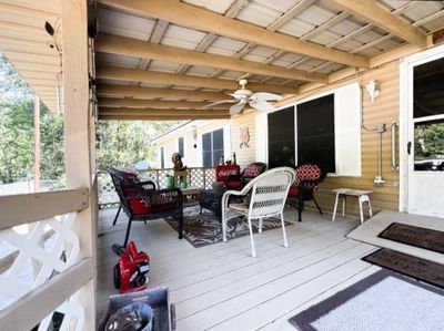 The spacious covered porch has a cozy seating area, perfect for relaxing outdoors. | Image 3