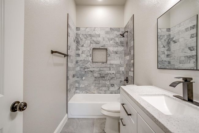 Full bathroom featuring washtub / shower combination, tile patterned flooring, vanity, toilet, and baseboards | Image 31