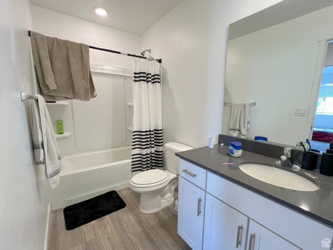 Bathroom featuring wood finished floors, vanity, toilet, and shower / tub combo | Image 6
