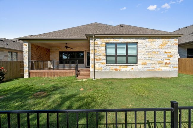 Back of property with a ceiling fan, stone siding, and a shingled roof | Image 30