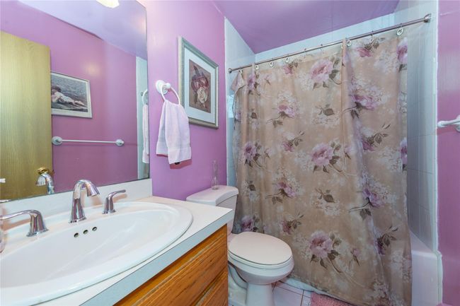 Full bath featuring tile patterned flooring, vanity, toilet, and shower / tub combo with curtain | Image 23