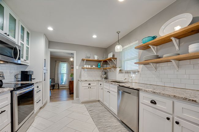 Kitchen with appliances with stainless steel finishes, open shelves, decorative backsplash, white cabinetry, and recessed lighting | Image 15