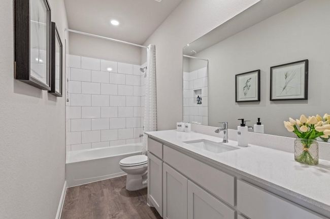 Bathroom featuring wood finished floors, vanity, and shower / bathtub combination with curtain | Image 22