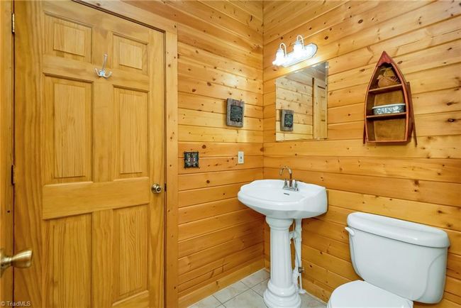 The basement-level den in the log cabin beckons with picturesque mountain views and French doors leading out to a charming outdoor area adorned with two swings, creating a serene retreat immersed in the beauty of nature. | Image 42