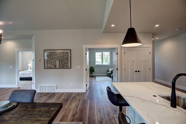 Kitchen with decorative light fixtures, light stone counters, dark wood-style flooring, recessed lighting, and a breakfast bar area | Image 10