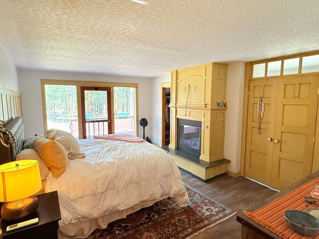 Bedroom with dark wood-type flooring, a textured ceiling, a fireplace, and access to outside | Image 35