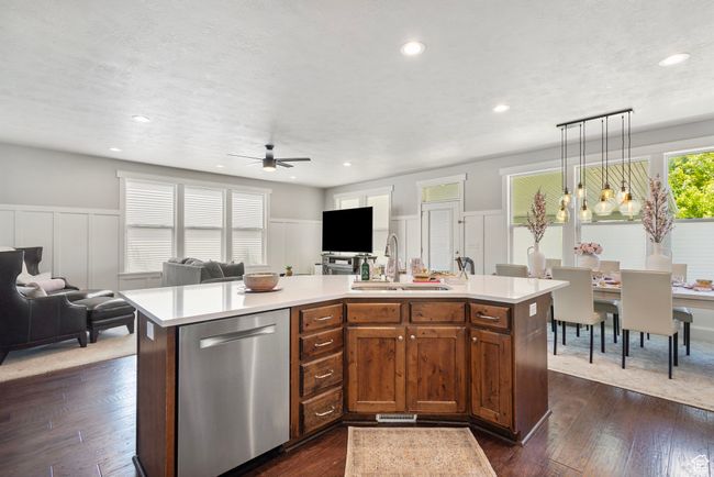 Kitchen with stainless steel dishwasher, open floor plan, a decorative wall, ceiling fan, and light countertops | Image 13