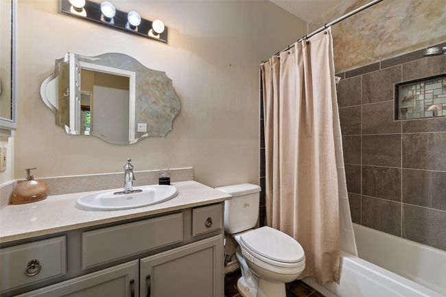 Bathroom with toilet, vanity, and shower / bathtub combination with curtain | Image 29