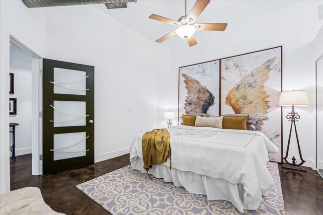 Primary bedroom with stained finished concrete flooring, a high ceiling, and ceiling fan | Image 26