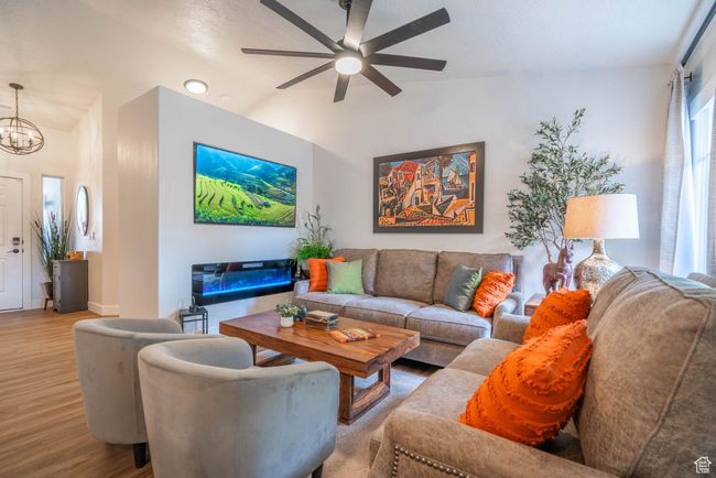 Living room featuring light hardwood / wood-style floors and ceiling fan with notable chandelier | Image 28