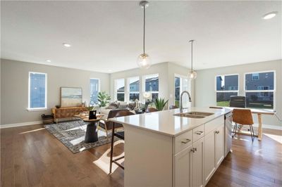 Kitchen featuring hardwood / wood-style floors, white cabinetry, sink, decorative light fixtures, and a center island with sink | Image 2