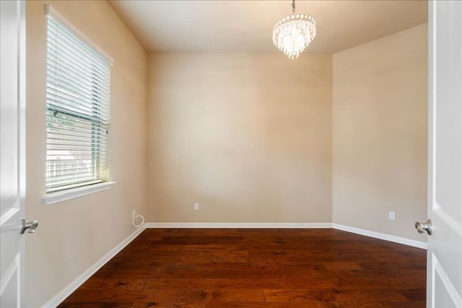The flex space features a chandelier, wood floors, and natural light. | Image 27
