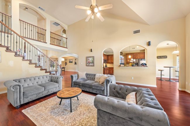 Living area with dark wood-type flooring, visible vents, baseboards, and a ceiling fan | Image 4
