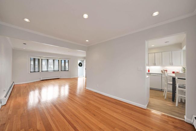 Unfurnished living room with a baseboard radiator, crown molding, and light hardwood / wood-style flooring | Image 7