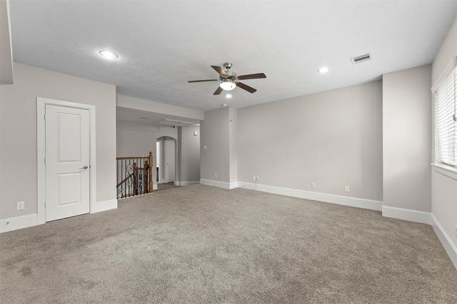 Upstairs, you’ll find a huge bonus room that’s perfect for game nights, movie marathons, or even a teen hangout. Plush carpet, ceiling fan, and big windows keep it bright and comfy. | Image 25