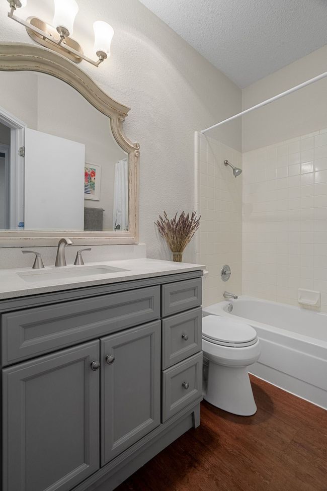 Bathroom with vanity, wood finished floors, shower / bath combination, and a textured ceiling | Image 23