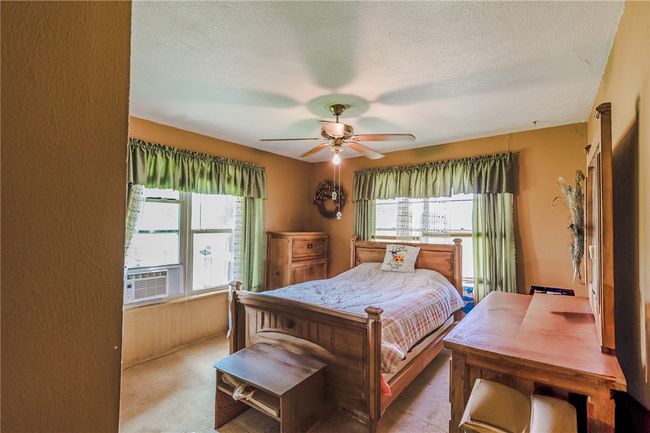 Carpeted bedroom with multiple windows, cooling unit, a textured ceiling, and a ceiling fan | Image 26