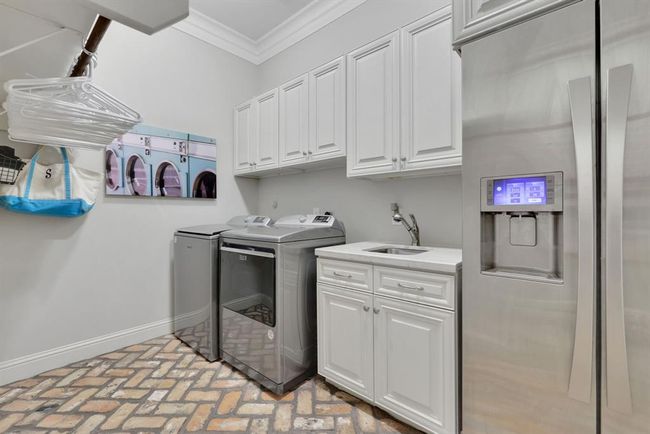 The oversized utility room includes built-in cabinetry with sink, hanging space, and a designated area for a full-size refrigerator. Such a functional layout with abundant storage. | Image 41