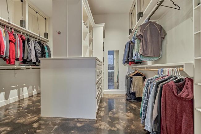 The primary closet is thoughtfully designed with dual sides, providing separate areas for enhanced privacy and convenience. Featuring a smart combination of open shelving, built-in drawers, and pull-down rods on the upper levels, this space is optimized for maximum storage and effortless organization. | Image 34